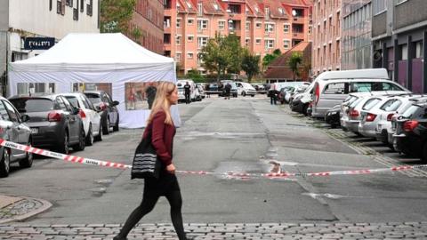 A woman passes by as Danish police technicians inspect the scene outside a local police station in Copenhagen on August 10, 2019