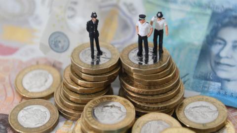 Plastic figure models of police officers on British sterling coins and bank notes