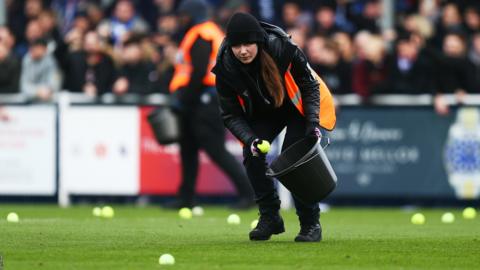 Stewards clear tennis balls from the Eastleigh pitch