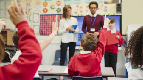 School children with hands up in classroom