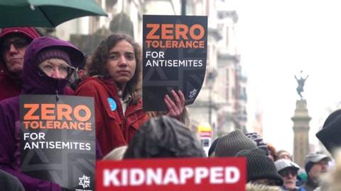 Protesters hold up sign saying 'zero tolerance for antisemites' at a march in central London