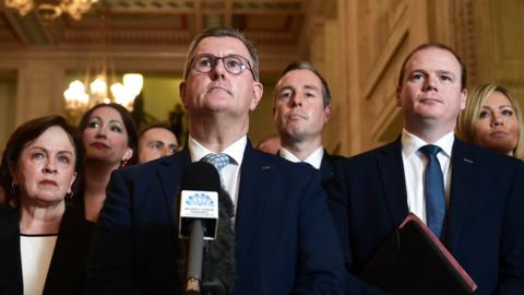 Sir Jeffrey Donaldson speaks to the media alongside party members at Stormont