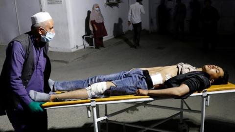 An Afghan man wheels an injured man in a hospital after a suicide bombing in Kabul, Afghanistan 24 October 2020