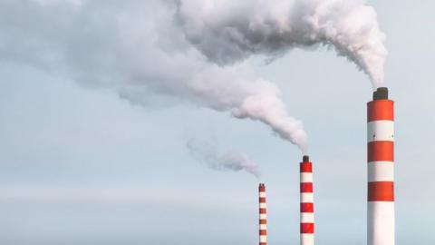 White smoke pouring out of the chimneys of the power plant.