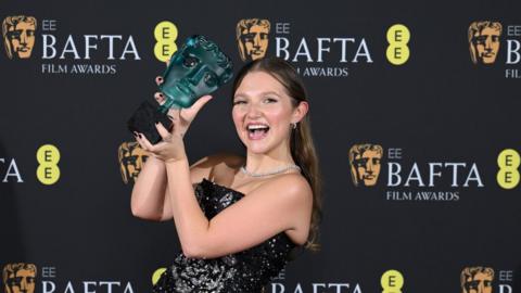 Mia McKenna-Bruce holding her EE Rising Star Bafta award