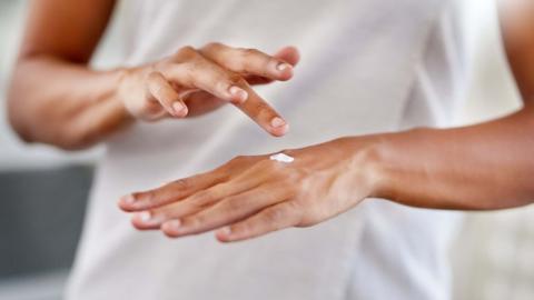 Woman putting cream on her hand