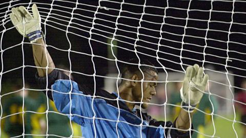 American Samoa goalkeeper Nicky Salapu clings to his own net forlorn.