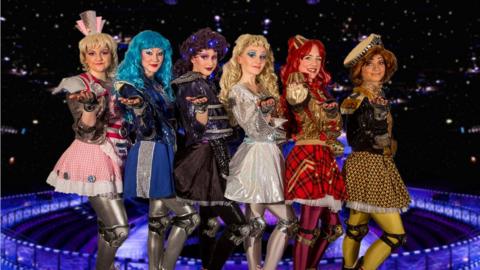 A group of performers from a Starlight Express production wearing long coloured wigs and futuristic costumes