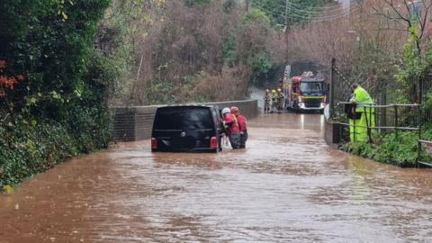 Rescuers freeing a car stuck in floodwater