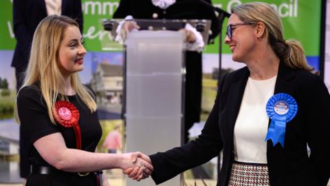 Labour Party candidate Gen Kitchen shakes hands with Conservative Party candidate Helen Harrison after being declared the winner in the Wellingborough by-election at the count centre in Kettering Leisure Village on February 16, 2024 in Kettering, England.