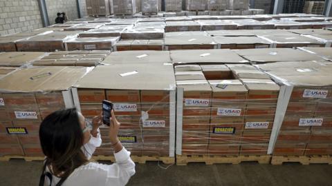 A woman photographs boxes containing humanitarian aid for Venezuela inside a warehouse at the Tienditas International Bridge in Cucuta, Colombia, on February 19, 2019