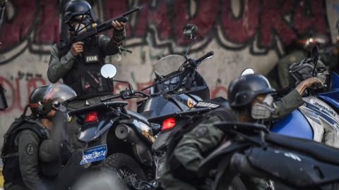 Venezuelan National Guard motorcyclists take cover after coming under fire during a skirmish in Caracas on July 30, 2017