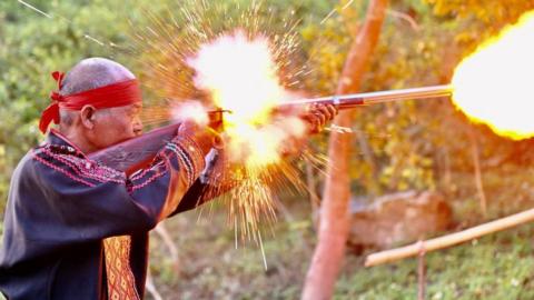 Taiwan indigenous priest firing a gun at a ceremony on 1 May 2021