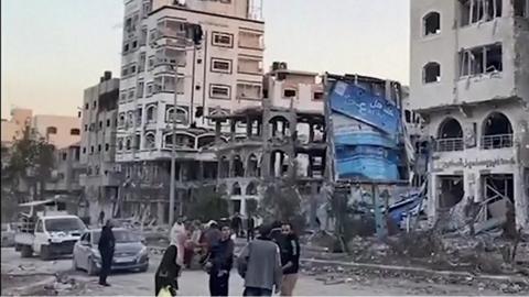 Residents of Gaza standing on the street surrounded by destroyed buildings