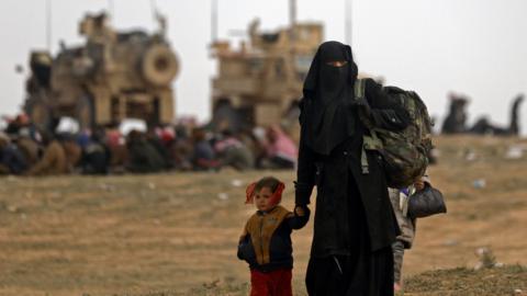 Civilians fleeing the Islamic State's group embattled holdout of Baghuz walk in a field on February 13, 2019