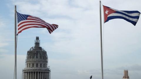 United States and Cuban flags fly side-by-side on the roof of the Iberostar Hotel Parque Central in Old Havana, Cuba.