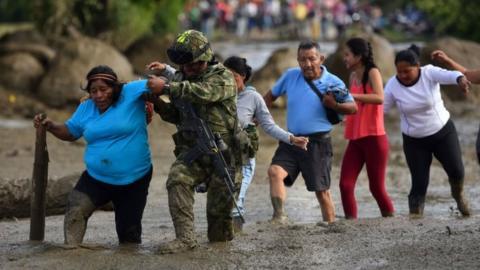 A soldier helps a woman walk through mud after a flooding of La Paila river in the municipality of Corinto, Department of Cauca, Colombia, 08 November 2017.