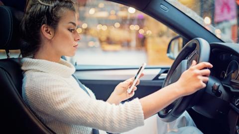 A woman using her phone while driving