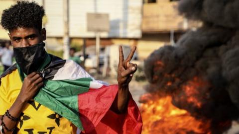 A Sudanese protester flashes the victory sign next to burning tires during a demonstration in the capital Khartoum, Sudan, 26 October 2021