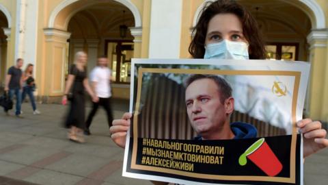 A woman in St Petersburg holds a placard with a photo of Mr Navalny in support of the opposition activist