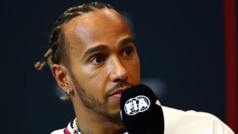 Lewis Hamilton holds a microphone during a press conference