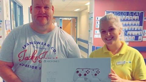 Steven Allenby and a member of staff at Leeds Children's Hospital holding an Xbox