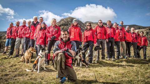 Mountain rescue volunteers pose in a line up