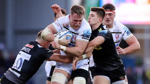 Jack Clement of Gloucester Rugby is tackled by Harvey Skinner and Joe Hawkins of Exeter Chiefs