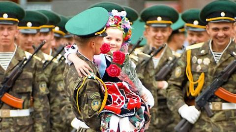 A girl in Ukrainian costume being lifted by a soldier