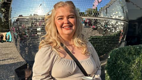 Image of Hattie. She is pictured outside near a large mirror ball.