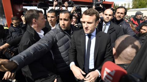 Emmanuel Macron (L) is surrounded by journalists as he talks to Whirlpool employees in front of the company plant in Amiens, France, 26 April