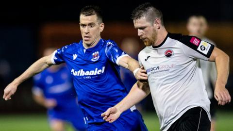 Penybont's Chris Venables in action against Jarrad Wright of Pontypridd United