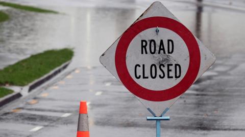 A sign on a flooded road saying "road closed"
