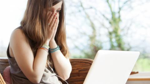 Girl covering face after looking at laptop