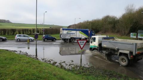 Cars and lorries driving through floodwater on the A35