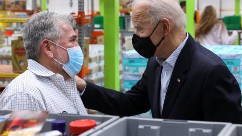 Biden touches a man's shoulder at a food bank