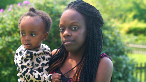 Tinu Alikor holding her daughter outside in a garden looking at the camera