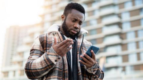 Person holding a phone looking frustrated