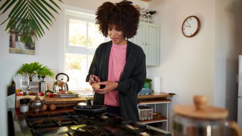 Woman cooks on a stovetop.