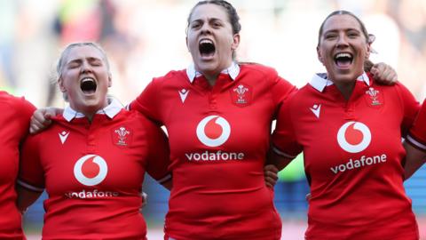 Alex Callender, Natalia John and Georgia Evans of Wales during the anthem before defeat to England