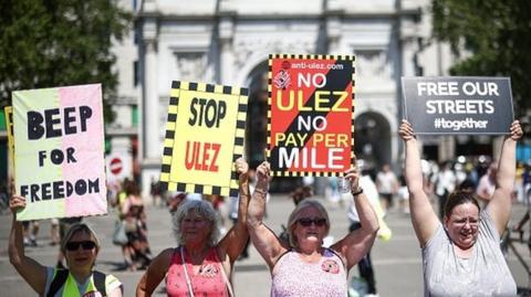 Demonstrators hold placards and chant slogans during a rally to protest against the expansion of Ulez
