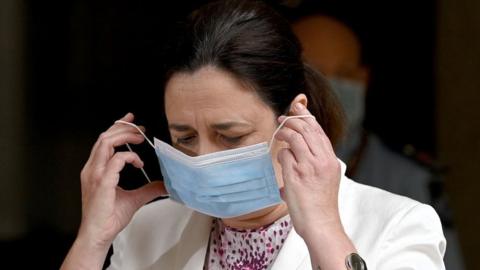 Queensland Premier Annastacia Palaszczuk takes off a mask