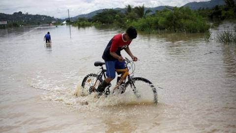 A child rides his bicycle on a flooded road during the passage of Storm Eta, in Pimienta, Honduras