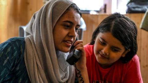 In this photo taken on August 17, 2019, Kashmiri Muslims talk to relatives on a landline phone in Srinagar