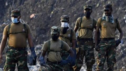 Sri Lankan military personnel stand among damaged homes at the site of a collapsed garbage dump in Colombo on April 16, 2017.