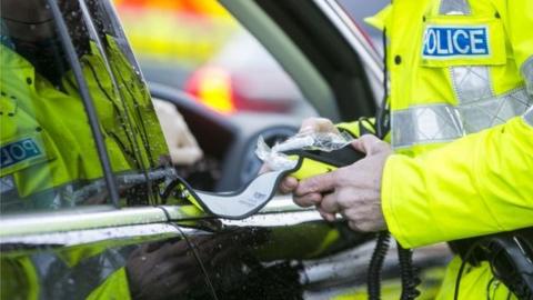 Police officer preparing to give motorist a breathalyser test