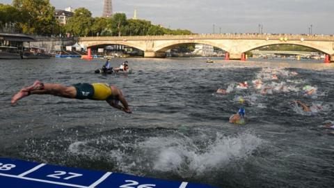 Triathlon athlete dives in the Seine river with The Eiffel Tower in the background