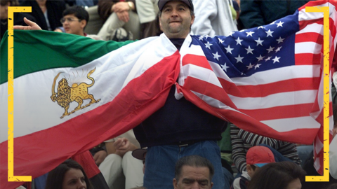 An Iran fan holds up the pre-revolution flag of Iran, and that of the USA