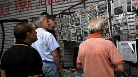 People read newspaper headlines in Athens on 27 June