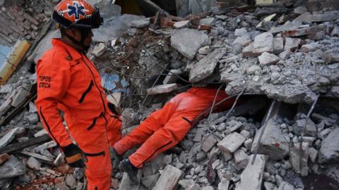 Man in jumpsuit with top half of his body under rubble